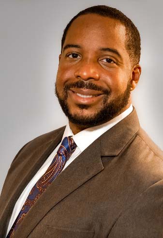 Dr. Terry Frazier is wearing a brown suit and multi-colored tie