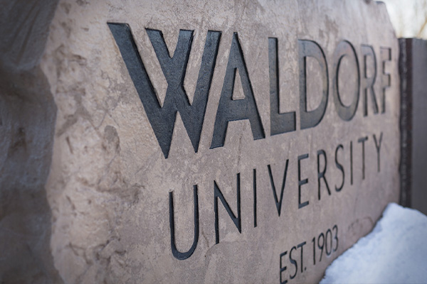 Closeup of Waldorf University stone sign with snow at base of sign