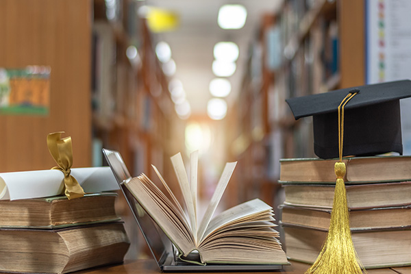 Stacks of books with graduation cap and scroll