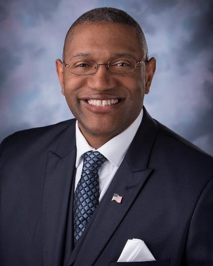 Dr. Ardrelle Evans is wearing a blue suit and tie with American flag pin