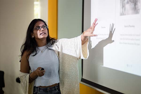 Teacher gestures toward projector slideshow