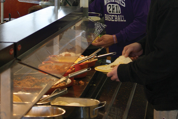 Closeup of a food buffet with students getting food