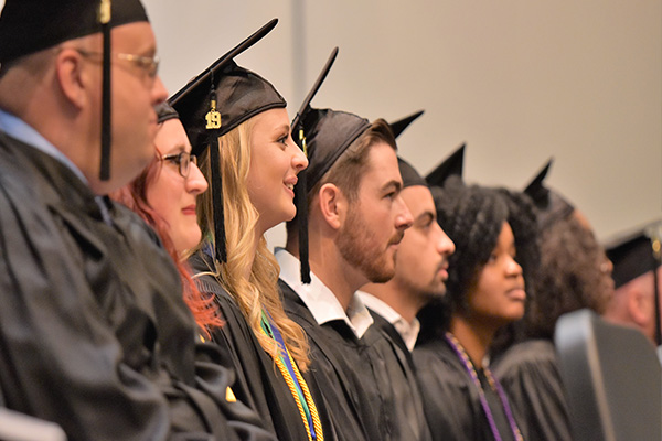 Row of smiling graduates during commencement ceremony